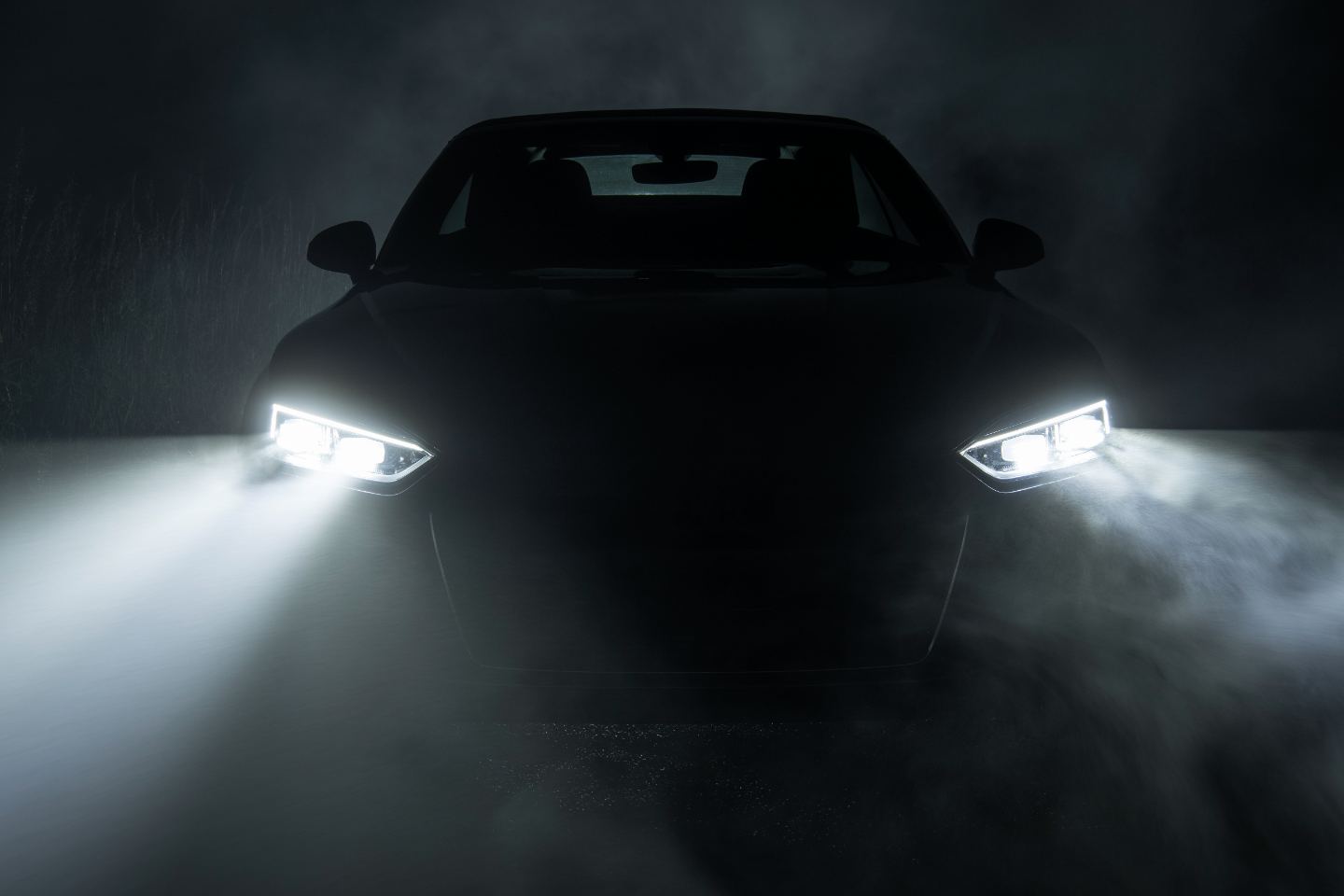 Vehicle headlights in dense fog at night