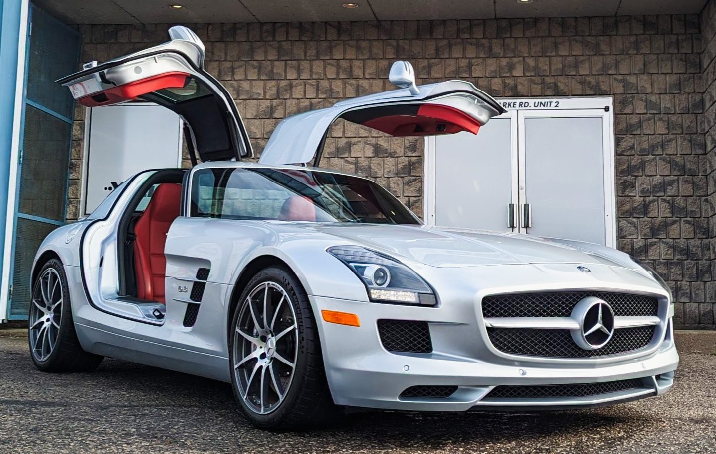 Silver Mercedes-Benz SLS AMG with gullwing doors open outside Auto Trim Design